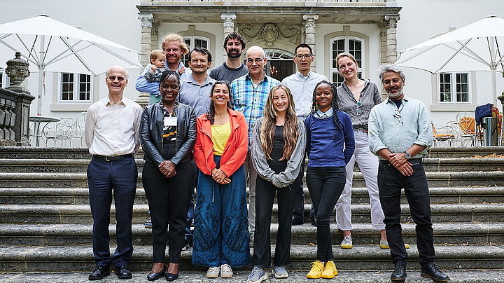 Gruppenfoto auf einer Steintreppe vor dem Eingang eines großen weißen Gebäudes