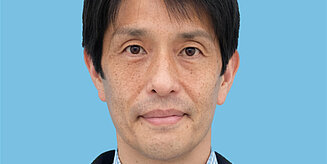 Portraitbild eines schwarzhaarigen, lächelnden Mannes: Naoki Yoshida